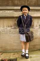 Smiling uniformed schoolgirl leaning against stone wall