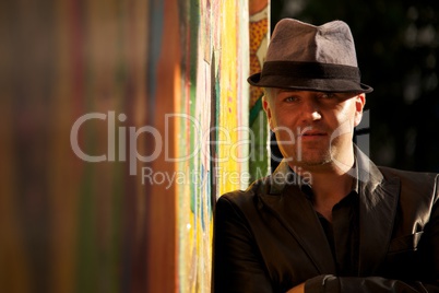 Sunlit man in hat beside colourful wall