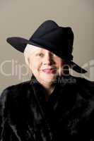 White-haired woman in black hat and coat