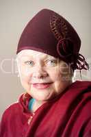 White-haired woman in maroon hat and shawl