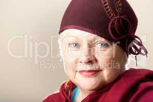 White-haired woman in red feathered hat and shawl