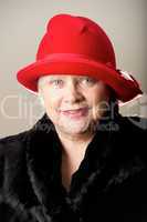 White-haired woman in red hat and fur