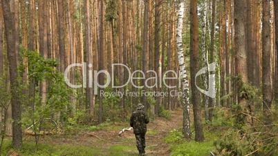 Man in camouflage walking on the footpath in summer forest