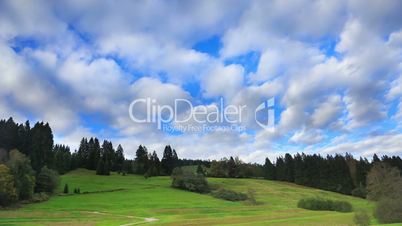 Fast cloud movement above green hill and forest, timelapse