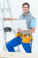 Electrician holding laptop by step ladder