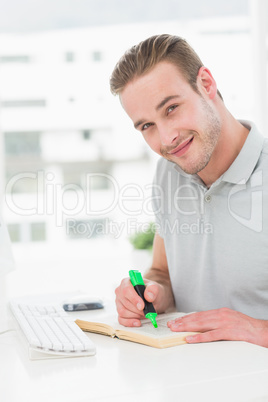 Cheerful casual businessman highlighting a book