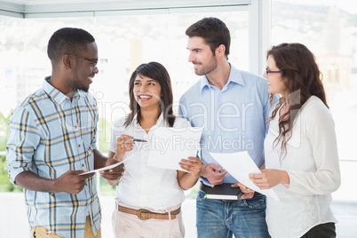 Smiling coworkers with files briefing together