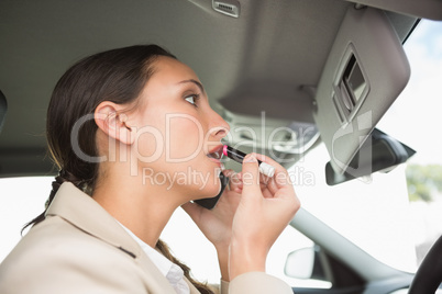 Businesswoman having a phone call while putting on lipstick