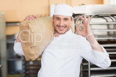 Smiling baker holding bag of flour