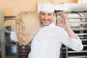 Smiling baker holding bag of flour