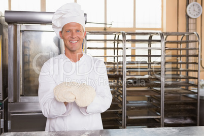 Smiling baker holding raw dough