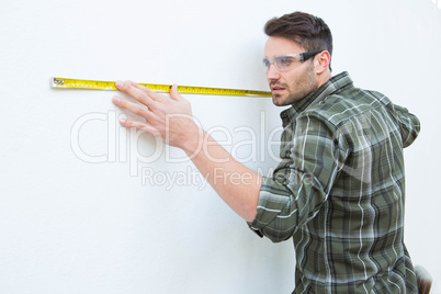 Carpenter measuging white wall