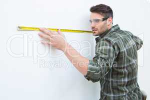Carpenter measuging white wall