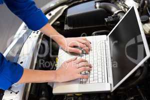 Mechanic using laptop on car