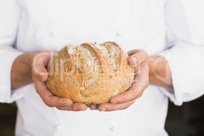 Baker showing freshly baked loaf