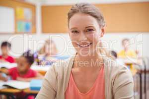 Pretty teacher smiling at camera at top of classroom