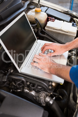Mechanic using laptop on car