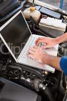 Mechanic using laptop on car