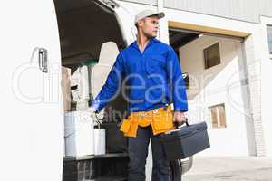 Serious handsome handyman holding toolbox