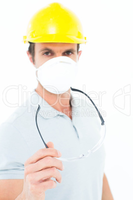 Worker wearing mask and hardhat while holding protective glasses