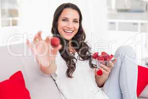 Pretty brunette eating strawberries on couch