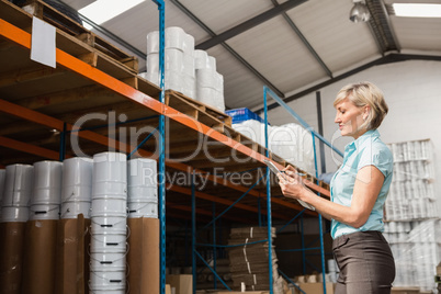 Warehouse manager checking her list on clipboard