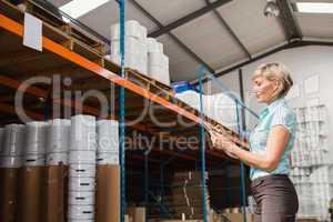 Warehouse manager checking her list on clipboard