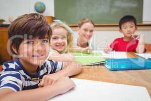 Pretty teacher helping pupil in classroom smiling at camera