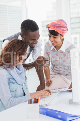 Happy coworkers speaking and using computer