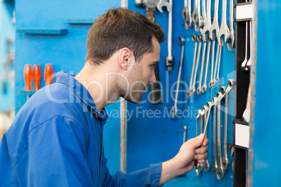 Mechanic taking a tool from wall