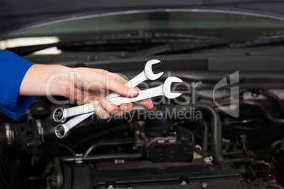 Mechanic holding pair of wrenches