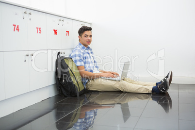 Smiling college student sitting on the floor with laptop