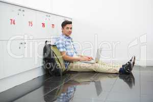 Smiling college student sitting on the floor with laptop