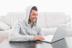 A smiling man using laptop at a table