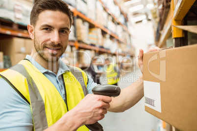 Warehouse worker scanning box while smiling at camera