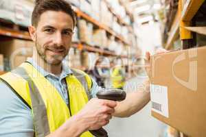 Warehouse worker scanning box while smiling at camera