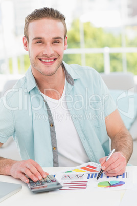 Smiling businessman working on measuring graph at his desk