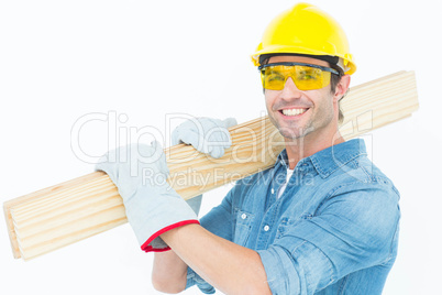 Carpenter wearing hardhat and glasses while carrying wooden plan