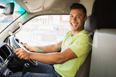 Delivery man driving his van while smiling at camera