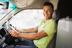 Delivery man driving his van while smiling at camera