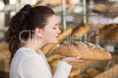 Pretty brunette smelling loaf of bread