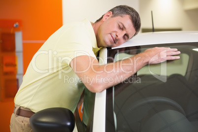 Smiling man hugging a white car