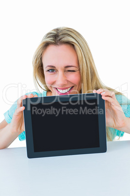 Smiling blonde showing tablet and winking