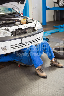 Mechanic lying and working under car