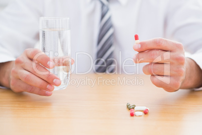 Casual businessman holding glass of water and tablet