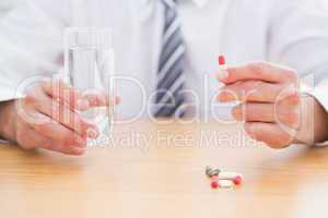 Casual businessman holding glass of water and tablet