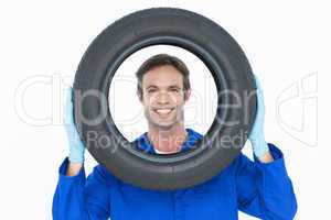 Confident mechanic looking through tire