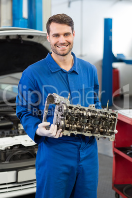 Smiling mechanic holding an engine Smiling mechanic holding an engine