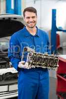 Smiling mechanic holding an engine