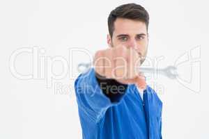 Confident young male mechanic holding spanner